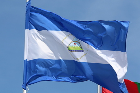 The Nicaragua national flag flutters in the wind on a flagpole.