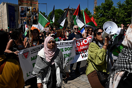 Palestinian protesters march holding a banner and flags while chanting slogans. Thousands of protesters take part in the annual Labor Day celebration (May Day) marking the international day of the workers.