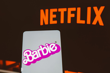 In this photo illustration, the Barbie the movie logo seen displayed on a smartphone with the Netflix streaming logo in the background.