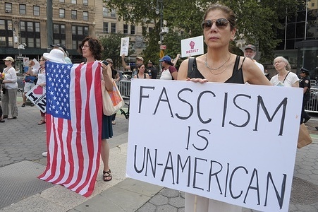 Anti-Trump demonstrators hold the American flag and a placard at a rally in Foley Square. Demonstrators in Manhattan, New York City protested against Donald Trump as part of a nationwide rally called “Good Trouble Lives On” honoring the late civil rights leader John Lewis. Protesters condemned the Trump administration’s immigration policies and U.S. Immigration and Customs Enforcement or ICE for arresting and deporting immigrants.