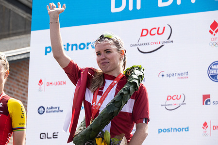 Gold medalist Alberte Emilie Greve of UNO-X MOBILITY waves from the podium during the medal ceremony after the Women's Elite Road Race at the Danish Championship 2025. When DM Week returns to Aalborg from 23-29 June 2025, there will be more sports than ever before, new disciplines on the program and an entire city in motion. During an intense week, some of Denmark's most talented athletes will compete for DM gold in over 120 disciplines - from classics like cycling and swimming to high diving from the Limfjord Bridge, dance, speedway and 3x3 basketball. This will be the fourth time DM Week has been held, and the third time Aalborg has hosted it.