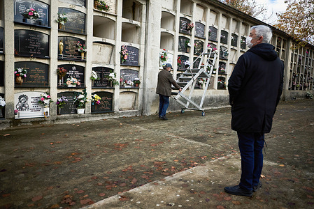 A man takes a ladder to access his relative's niche, while another observes and prays to his relatives at the cemetery of Pamplona.
Hundreds of parishioners of the Catholic Church have gathered in the cemetery of Pamplona to pray for the memory of their passed relatives.