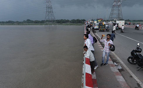 People watch as the swollen Yamuna River overflows near the Inter-State Bus Terminal (ISBT). Heavy discharge from the Hathinikund Barrage in Haryana caused the Yamuna River to rise to 207.41 meters, surpassing the danger mark of 205.33 meters, following heavy rainfall in the Himalayan region.