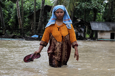 A local woman seen in the street during the flood.
Heavy rain and strong winds struck Aceh Province causing massive flooding in Aceh Utara District, Aceh, Indonesia. Floods as high as 1 meter rush in because of damaged river dikes, resulting in thousands of residential houses submerged and damaged. From the report of Meteorology Climatology and Geophysics Agency (BMKG), Indonesia in the next few days will continue to adversely affect the weather, such as heavy rain, strong winds, lightning, high waves and landslides.