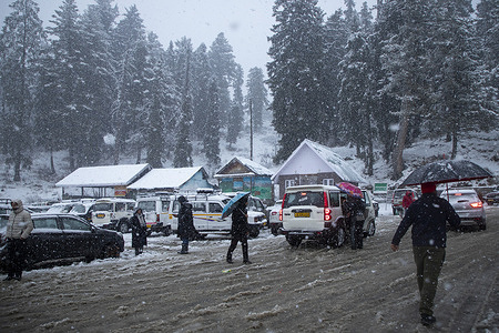 People walk amid heavy snowfall in ski resort Gulmarg, north of Srinagar. A much-awaited spell of snowfall at most popular tourist sites in the Himalayan Kashmir on Sunday brought cheer and joy to tourists as well as stakeholders in the tourism sector. The wet weather also ended a prolonged and alarming dry spell in the region.