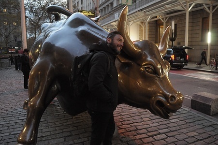 A person takes photos by the "Charging Bull" statue in the Financial District in Manhattan, New York City.