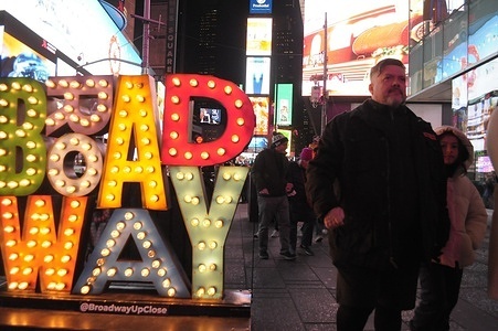 People walk past a Broadway sign in Times Square, Manhattan, New York City.