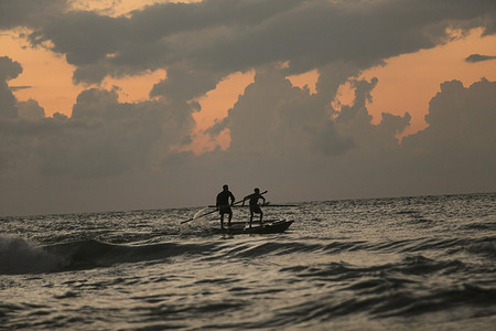 Palestinian refugees are fishing on a small boat at the beach in the west of Gaza City.