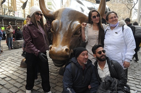 People take photos by the "Charging Bull" statue in the Financial District in Manhattan, New York City.