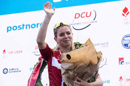 Gold medalist Alberte Emilie Greve of UNO-X MOBILITY waves from the podium during the medal ceremony after the Women's U23 Road Race at the Danish Championship 2025.