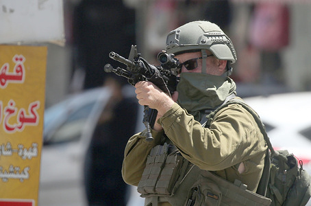 An Israeli soldier aims his weapon, during a military operation in neighborhoods of the Askar refugee camp east of Nablus in the West Bank. The raid is part of a broader military campaign targeting refugee camps in the West Bank. The Israeli government has threatened to occupy refugee camps, in areas under the control of Palestinian President Mahmoud Abbas.