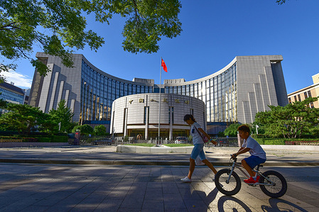 A kids rides past the headquarters building of the people's Bank of China in Beijing.
The People's Bank of China is the central bank of the People's Republic of China responsible for carrying out monetary policy and regulation of financial institutions in mainland China, as determined by People's Bank Law and Commercial Bank Law.