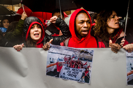 Two activists of Open Arms seen displaying posters. Open Arms has gathered hundreds of people outside the Barcelona Italian Embassy in protest at the retention of one of its rescue boats and the serious allegations by Sicilian prosecutors.The direction of Open Arms is facing 15 years in prison and heavy fines for doing their job saving lives following allegations of prosecutors of Sicily (Italy) for trafficking and criminal association.