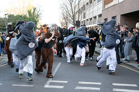 People in horse costumes seen racing on the road. People in traditional pantomime horse costumes raced through the streets of Greenwich as the London Pantomime Horse Race returned for its 12th edition combining festive humour with charity. The light-hearted event saw costumed pairs compete along a short course while entertaining crowds.