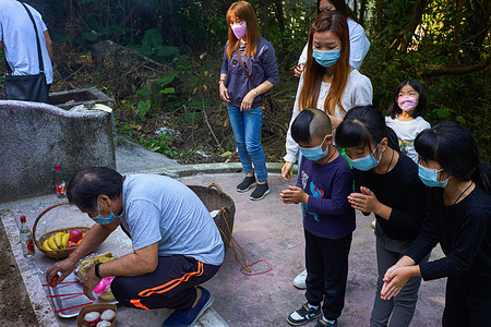 A family prays at a grave in a Chinese Hung Shui Kiu cemetery in Hong Kong to honor their ancestors. Chinese people visit cemeteries to honor their ancestors on 'Grave Sweeping Day', called the Qing Ming Festival in Hong Kong