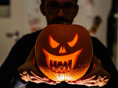 A man is seen holding a scary pumpkin. During the Halloween season, people visited a farm close to the city of Nijmegen to buy pumpkins with carved scary faces.