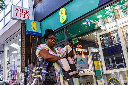 A lady walk past EE (formerly Everything Everywhere) store, a British national mobile network operator and internet service provider, which is a brand within the BT Group. EE is the second-largest mobile network operator in the United Kingdom.