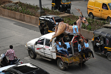 People are seen transporting a big sculpture of a deer on a towing truck in Mumbai.