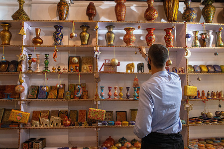 A man arranges Papier-mache items at a showroom in Srinagar.