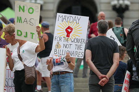 Demonstrators hold placards on the steps of the Pennsylvania State Capitol for a May Day protest against the policies of the Trump administration.