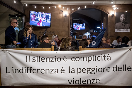 Protesters sit in a bar with a banner saying "Silence is complicity" during the rally. A peaceful sit in protest, organized by activists from various associations to express dissent on the Government's choices on Palestine in Lamezia Terme.