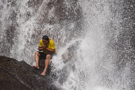 A man sits under a waterfall in Morazan. Central America has been hit by the "El Niño" phenomena, marking the region with strong heat waves and drought.