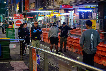 Victoria Police officers search a man at a restricted access point in Melbourne’s CBD on New Year’s Eve as road closures and barriers are enforced as part of the city’s security operation. A heightened police presence was visible across the Melbourne CBD on New Year’s Eve 2025 as authorities implemented additional security measures in response to recent national security concerns following the Bondi attack. Armed police and uniformed officers patrolled major public spaces, transport hubs, and entertainment precincts as large crowds gathered to welcome the New Year. Police said the increased visibility was part of a broader public safety operation aimed at reassuring the community and ensuring celebrations could proceed safely.