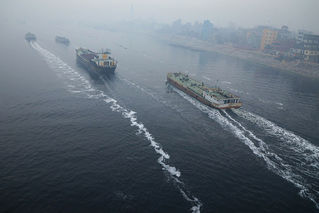 Cargo boats cross over the pitch-black polluted water of the Buriganga River in Dhaka.