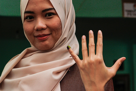 An Indonesian woman seen showing her inked finger after casting her vote during the general elections.Indonesians elect their president and vice president as well as members of the House of Representatives, Regional Representative Council and provincial and municipal councils.