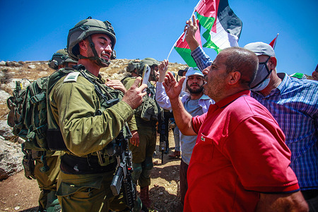 An Israeli soldier filming a Palestinian protester during a confrontation at the demonstration against Israeli settlements in the village of Beit Dajan near the West Bank city of Nablus.