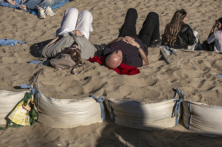 Two people are seen sunbathing on sandbags at Barceloneta beach. Holy Week comes to an end with high tourist occupancy in Barcelona. Tourists and residents alike are enjoying Barcelona's beaches in search of rest and sun on Easter Sunday.