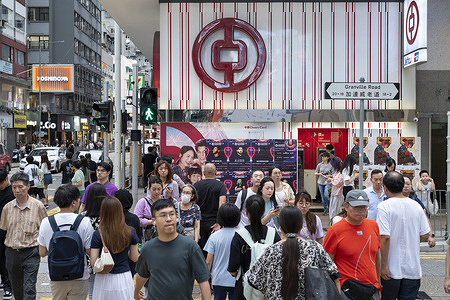 Pedestrians cross the street in front of the Chinese state-owned commercial banking company Bank of China branch.