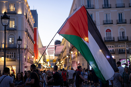 A protester carries a Palestinian flag during a nighttime demonstration by Palestinian supporters against the Israeli attacks on Gaza in Plaza del Sol.