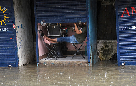 A man checks his mobile phone at his shop flooded with water caused by heavy rain in Mumbai. Traffic on the roads and railway lines was delayed due to heavy rain and flooding. Schools and colleges remained closed, and many offices allowed employees to work from home. The India Meteorological Department (IMD) issued a red alert warning of extremely heavy rainfall until Wednesday, advising citizens not to venture out unless necessary..