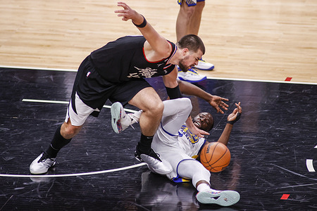 Los Angeles Clippers center Ivica Zubac (L) and Golden State Warriors forward Draymond Green (R) vie for the ball during an NBA basketball game at Crypto.com Arena in Los Angeles.