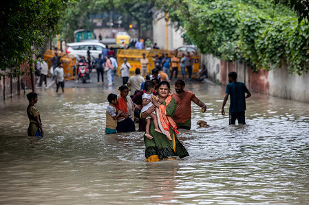 People wade through a flooded road after a rise in the water level of the river Yamuna following heavy monsoon rains in New Delhi. The government issued flood warnings and asked people living close to the riverbed or low-lying areas to evacuate their homes.