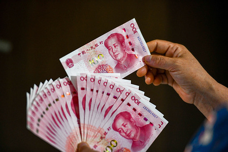 In this photo illustration, a person seen holding RMB 100 yuan banknotes.