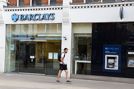 A man walks past a Barclays bank branch.
