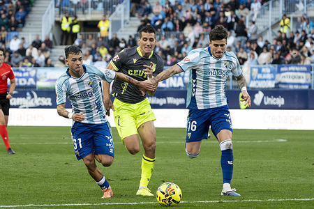 Rafael Garrido (L) and Diego Murillo (R) of Malaga CF and Aisar Ahmed Ahmed (C) of AD Ceuta seen in action during the LaLiga Hypermotion 2025/2026 match between Malaga CF and AD Ceuta at La Rosaleda stadium. Final score: Malaga CF 2:1 AD Ceuta