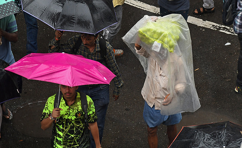 A vegetable vendor (R) seen carrying a sack on his head on the street during heavy rain. Incessant rain lashed the city since Friday night leading to water-logging and traffic snarls. Indian Meteorological Department (IMD) has issued a red alert warning for the citizens asking people to stay indoors unless necessary.