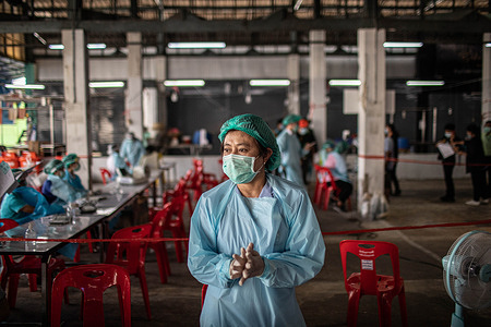 A health worker cleans her hands with hand sanitiser at the Bang Khae Market during a mass vaccination program in Bangkok, Thailand on March 18, 2021. The Bangkok Metropolitan Administration (BMA) started a mass vaccination program inside the closed Bang Khae Market after 224 cases of Covid-19 were found among residents in and around the market. A total of 6000 doses will be administered for the next few days the governor said.