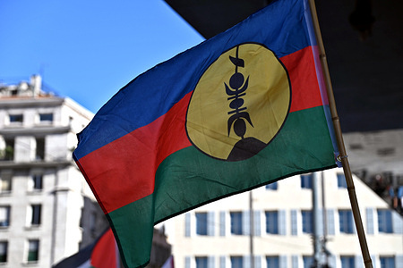 A protester holds a Kanak flag during an anti-colonialist rally. The activists in Marseille rally against colonialism in places like Palestine and Kanaky (New Caledonia). Groups such as FUIQP (United Front of Immigrations and Working-Class Neighborhoods) and Stop Arming Israel 13 denounce France’s colonial legacy. The Kanak flag, a symbol of New Caledonia’s indigenous struggle, has re-emerged amid recent pro-independence unrest.