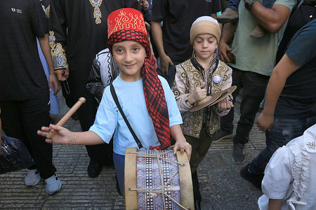 Palestinian children also joined in the celebrations at the central market in Nablus's Old City in the West Bank to mark the Prophet Muhammad's birthday. The participants, dressed in traditional clothing, chanted religious hymns accompanied by tambourines and drums during the celebrations and distributed sweets in the market square to commemorate the birthday of Prophet Muhammad.