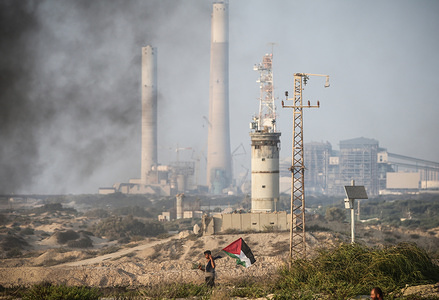 Israeli soldiers monitors the situation from a guard post as a Palestinian protester runs with his national flag on the beach near the border with Israel, in the northern Gaza Strip, during a demonstration calling for the lift of the Israeli blockade on the coastal Palestinian enclave.