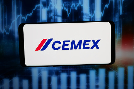 In this photo illustration, the logo of Mexican building materials company Cemex is displayed on a smartphone in front of abstract background on computer screen.