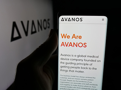 In this photo illustration, a person is holding a smartphone with the webpage of US healthcare company Avanos Medical Inc. on screen in front of logo.