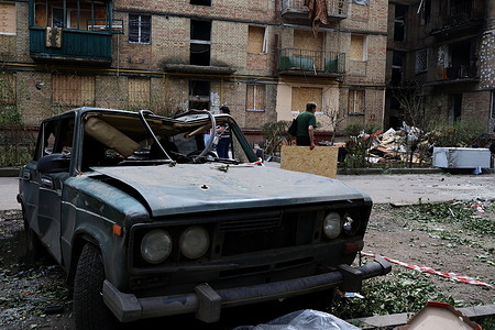 A man carries plywood behind a damaged car near a residential building that was heavily damaged by Russian missile strikes amid the Russian invasion of Ukraine. In the early morning of June 17, the Russian army attacked the Ukrainian capital with missiles and Shahed-type combat drones, resulting in destruction and damages to residential buildings in different parts of the city. At least 28 people were killed and 140 were injured in Kyiv. For the second day in a row, rescuers cleared up rubbles of destroyed buildings and searched for dead bodies.