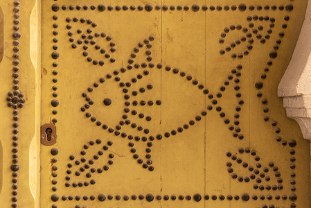View of the distinctive fish design, and architectural detail of a traditional yellow-painted door in the Medina of Tunis.
