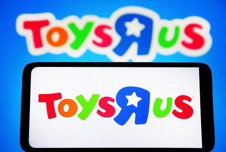 In this photo illustration, a Toys "R" Us logo is seen on a smartphone and in the background.