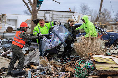 Volunteers help remove items from a damaged home for a family with a baby after a tornado in Sullivan, Indiana. Three people were declared dead, and 8 others were injured, as the search and rescue operation continued Saturday afternoon. The severe storm that created the tornado struck Friday, March 31, 2023, and damaged about 150 homes and structures in Sullivan.